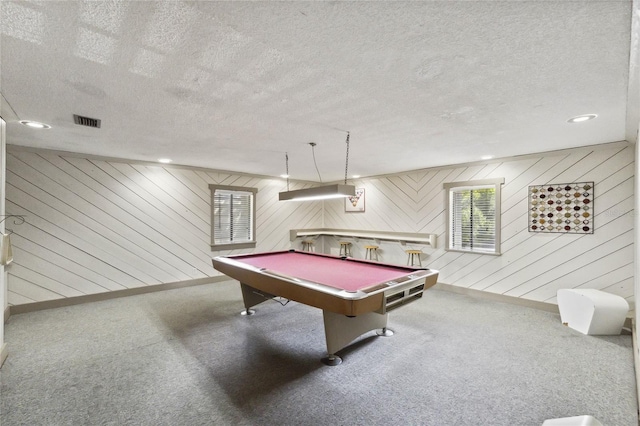 rec room with wood walls, pool table, and a textured ceiling