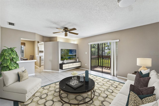 living room with ceiling fan, a textured ceiling, and light tile patterned floors