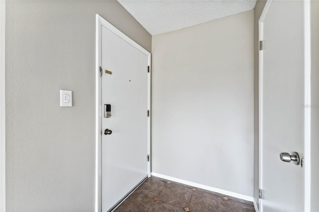 doorway with dark tile patterned flooring and a textured ceiling