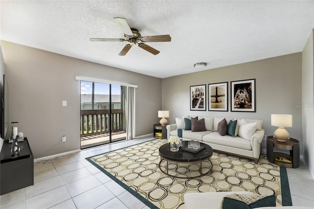 living room featuring light tile patterned flooring, ceiling fan, and a textured ceiling