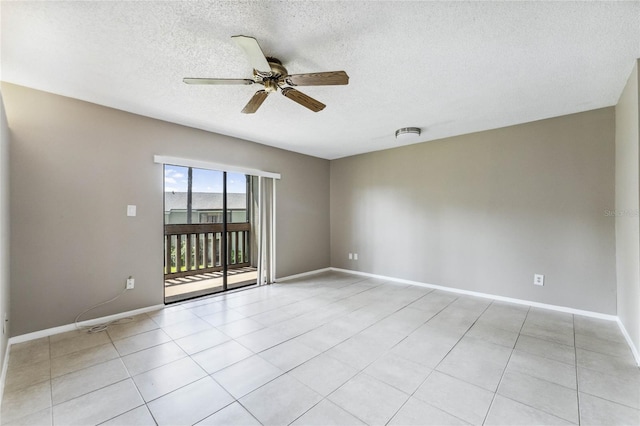 empty room with ceiling fan, light tile patterned floors, and a textured ceiling