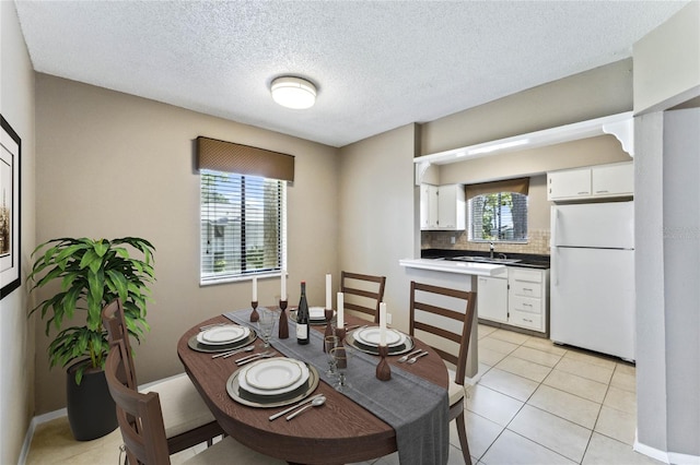 tiled dining area with plenty of natural light, sink, and a textured ceiling