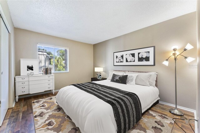 bedroom with a closet, dark hardwood / wood-style floors, and a textured ceiling