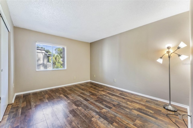 spare room with a textured ceiling and dark hardwood / wood-style flooring