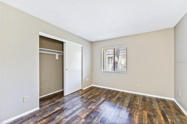 unfurnished bedroom with a closet, dark hardwood / wood-style floors, and a textured ceiling