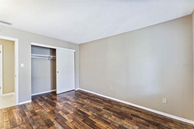 unfurnished bedroom with a textured ceiling, a closet, and dark hardwood / wood-style floors