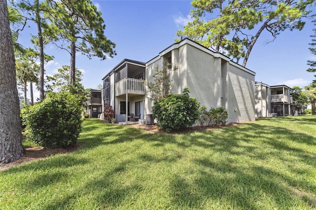 rear view of property with a yard and a balcony