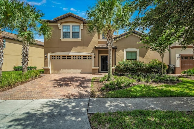 mediterranean / spanish house with decorative driveway, a tile roof, and stucco siding