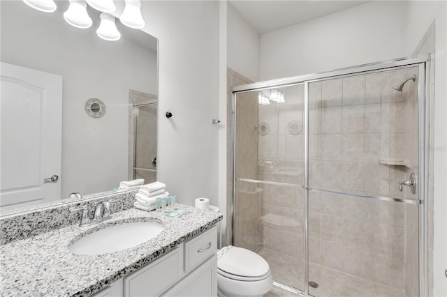 bathroom featuring toilet, a shower stall, and vanity