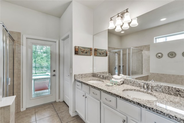 bathroom with double vanity, a stall shower, tile patterned flooring, and a sink