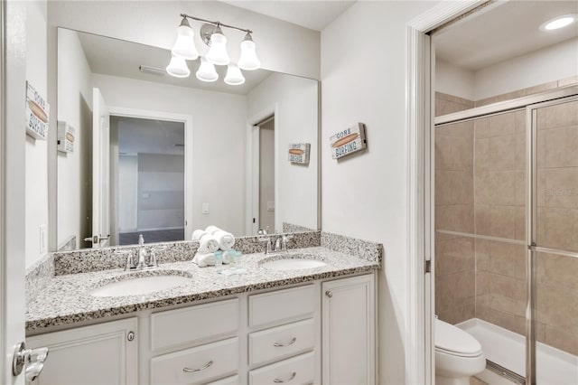 full bath with a stall shower, a sink, toilet, and double vanity