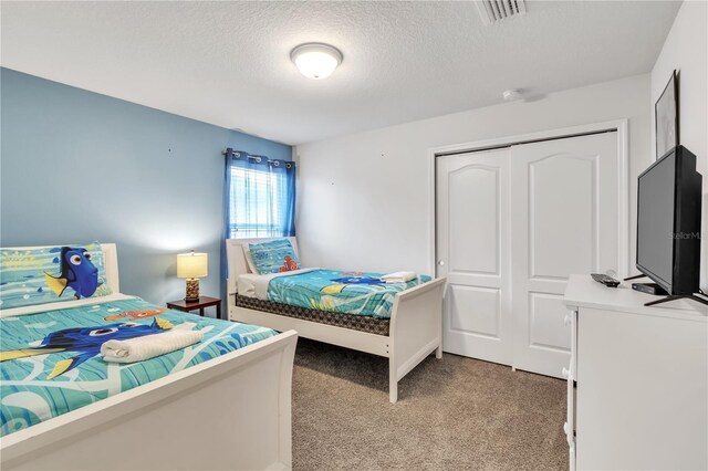 bedroom featuring light carpet, a textured ceiling, visible vents, and a closet