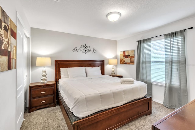 bedroom with light carpet, baseboards, and a textured ceiling