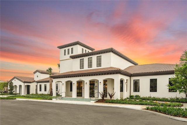 mediterranean / spanish house featuring covered porch, a tiled roof, and stucco siding