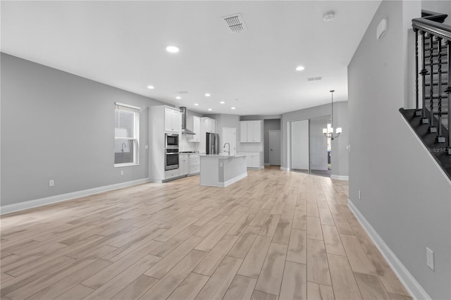 unfurnished living room featuring sink, light hardwood / wood-style flooring, and a notable chandelier