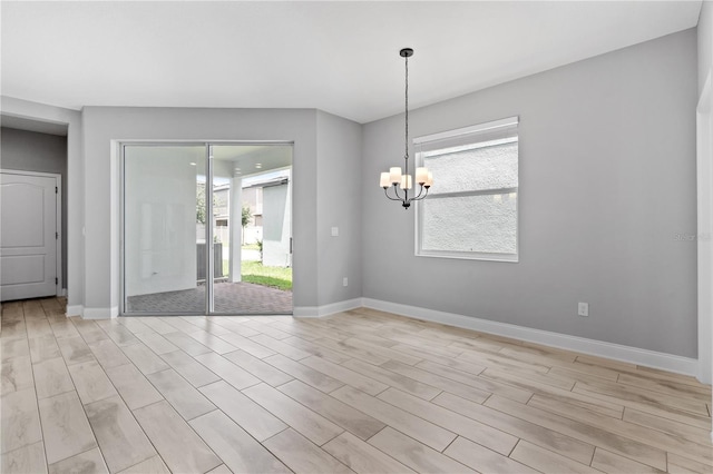 empty room with a chandelier and light wood-type flooring