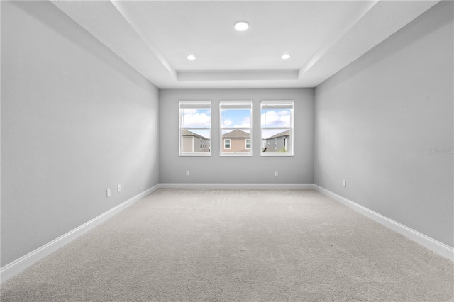 carpeted empty room featuring a tray ceiling