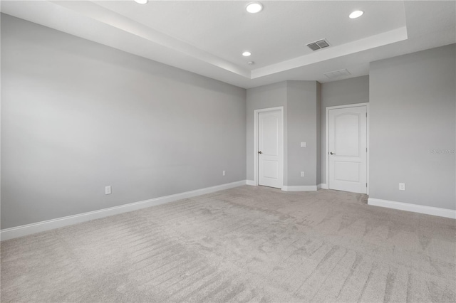 carpeted spare room featuring a tray ceiling