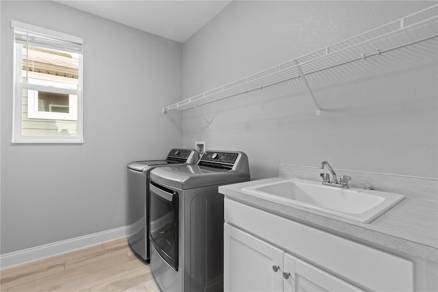 washroom with separate washer and dryer, sink, cabinets, and light wood-type flooring