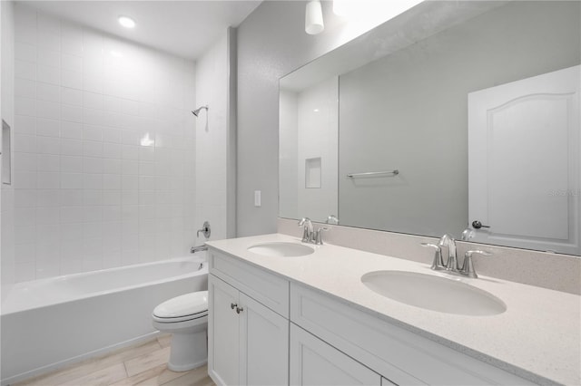 full bathroom with hardwood / wood-style flooring, tiled shower / bath, vanity, and toilet