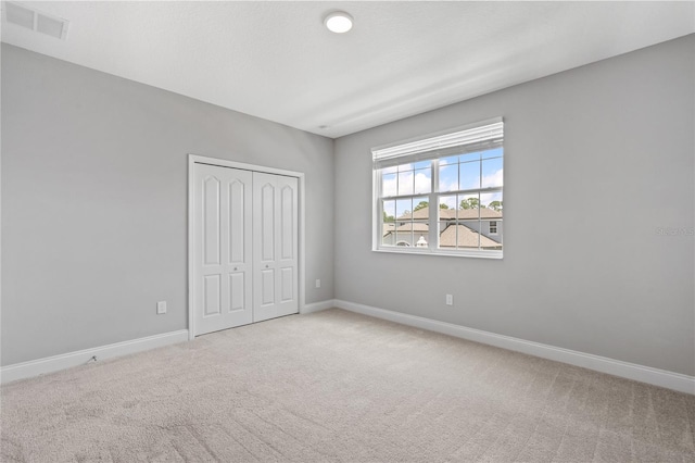 unfurnished bedroom featuring light colored carpet and a closet