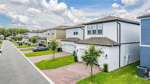 view of side of property featuring a garage, central AC unit, and a lawn