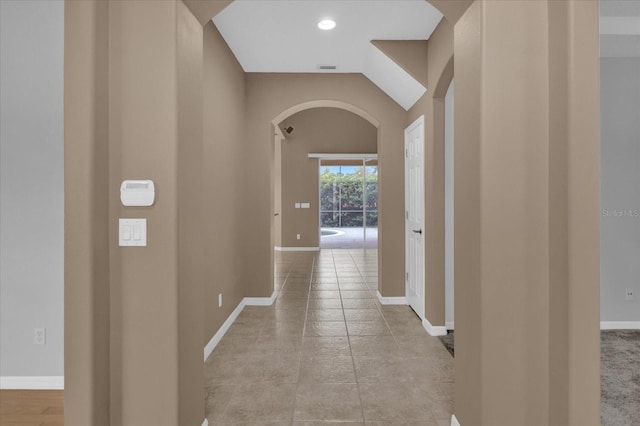 hallway featuring vaulted ceiling and light tile patterned floors