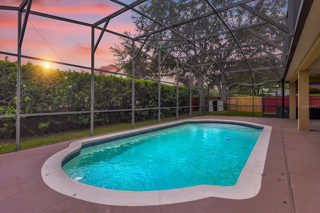 pool at dusk with a patio area and glass enclosure