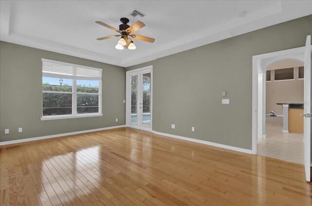 unfurnished room featuring a raised ceiling, french doors, light tile patterned floors, and ceiling fan