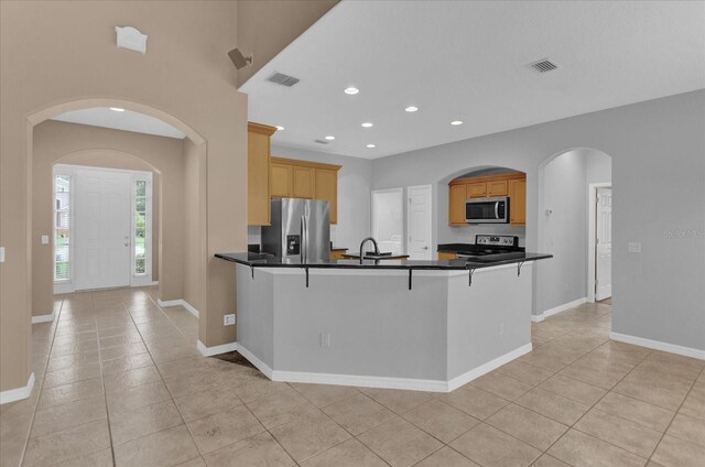 kitchen with stainless steel appliances, light brown cabinets, light tile patterned floors, and kitchen peninsula