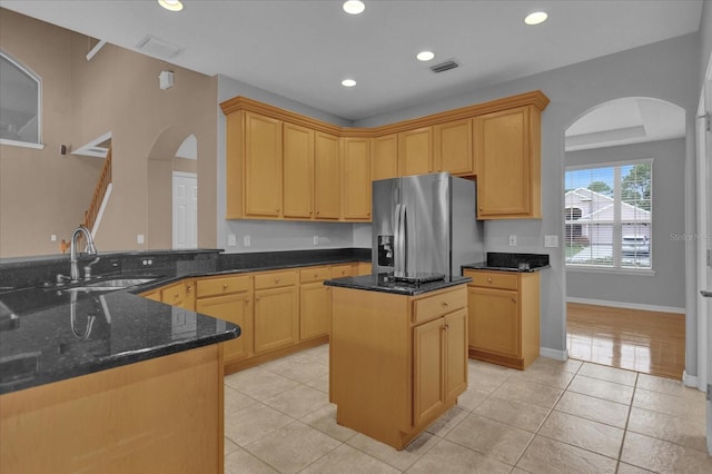 kitchen featuring sink, stainless steel fridge with ice dispenser, light wood-type flooring, and dark stone counters