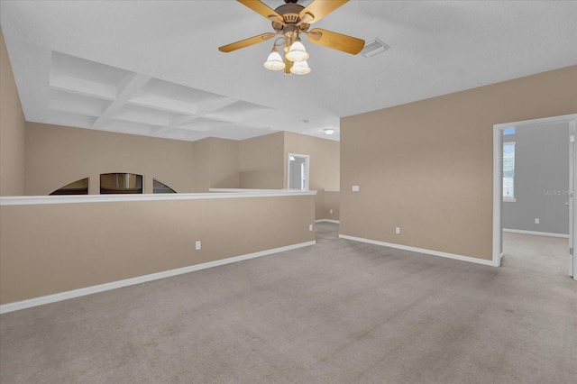 empty room with beamed ceiling, light colored carpet, coffered ceiling, and ceiling fan