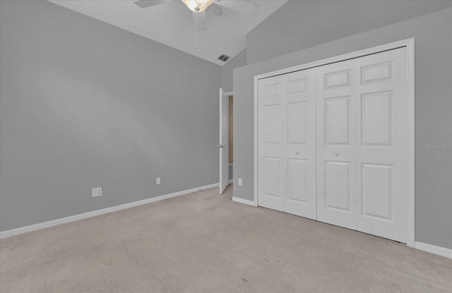 unfurnished bedroom with light carpet, ceiling fan, vaulted ceiling, and a closet