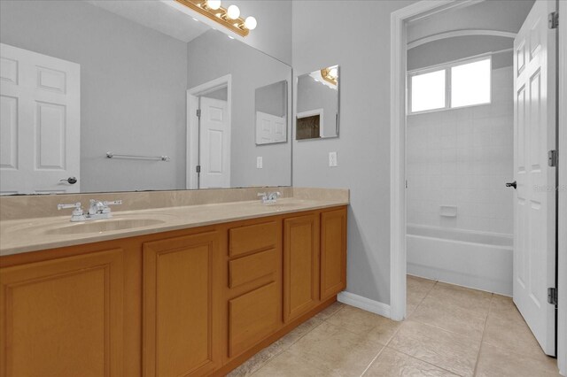 bathroom featuring tiled shower / bath, tile patterned flooring, and dual bowl vanity