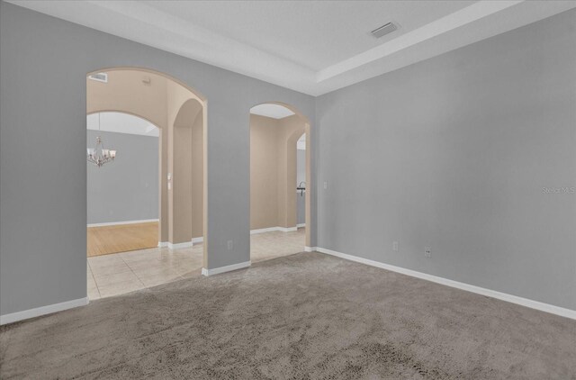 spare room with light colored carpet and a chandelier