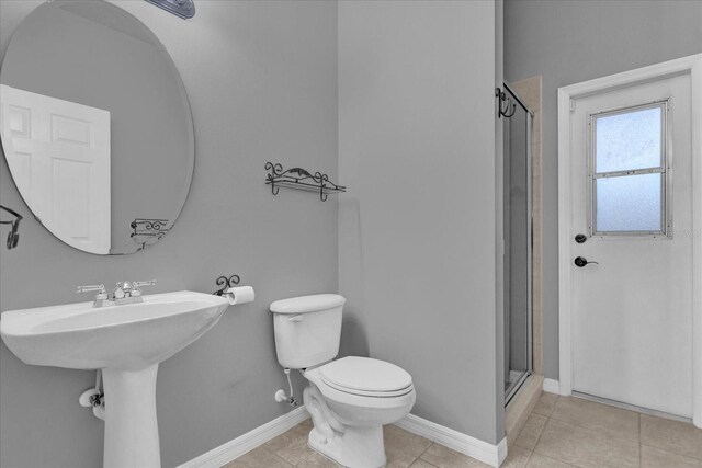 bathroom with a shower with shower door, tile patterned floors, and toilet