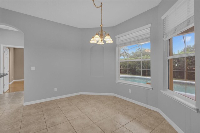 spare room featuring light tile patterned floors and a chandelier