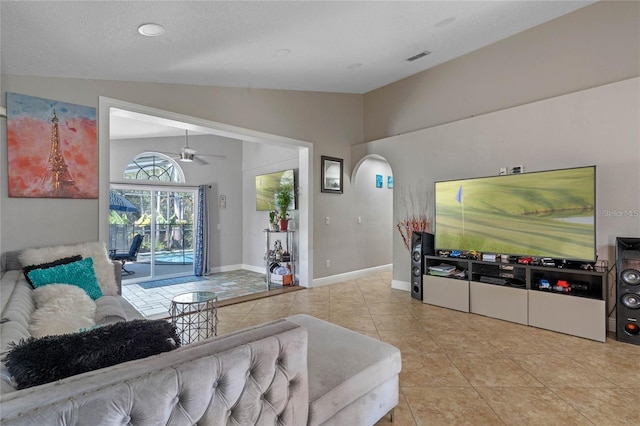 living room with ceiling fan, a textured ceiling, lofted ceiling, and light tile patterned floors