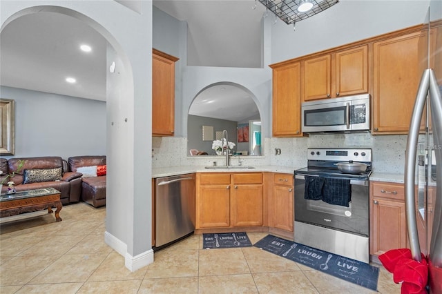 kitchen with light tile patterned floors, light countertops, appliances with stainless steel finishes, and a sink