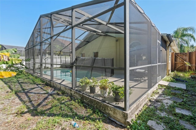 rear view of house with a fenced in pool, glass enclosure, and fence