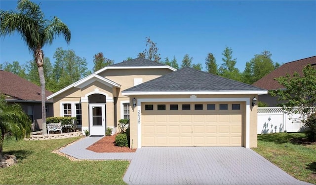 ranch-style house featuring a garage, decorative driveway, fence, and stucco siding