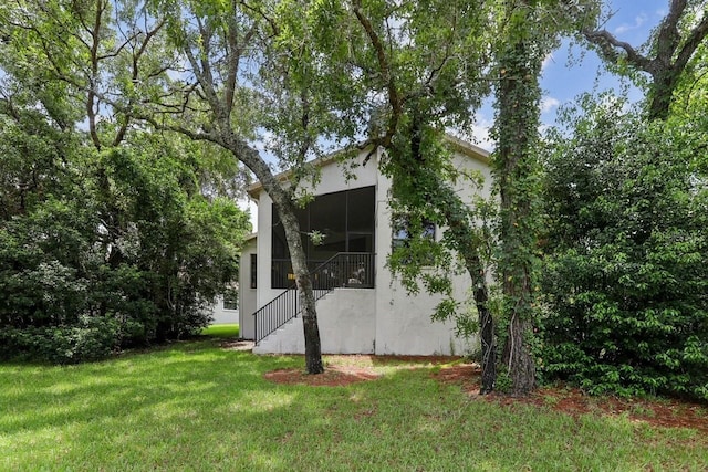 view of side of property with a yard, a sunroom, and ceiling fan