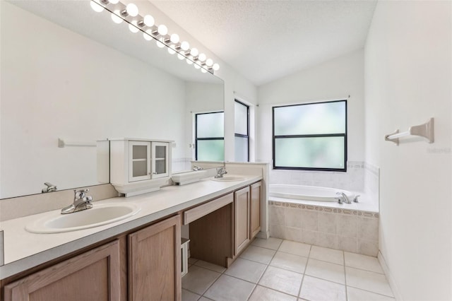 bathroom with lofted ceiling, a relaxing tiled tub, vanity, a textured ceiling, and tile patterned floors