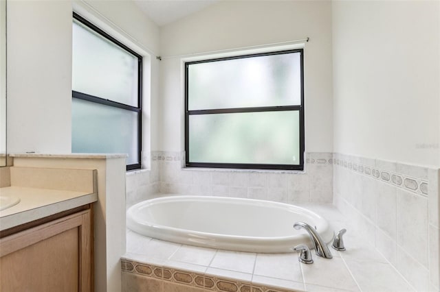 bathroom with tiled tub and vanity