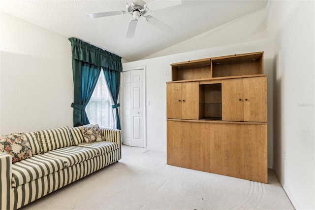 living room featuring light carpet, ceiling fan, vaulted ceiling, and a textured ceiling