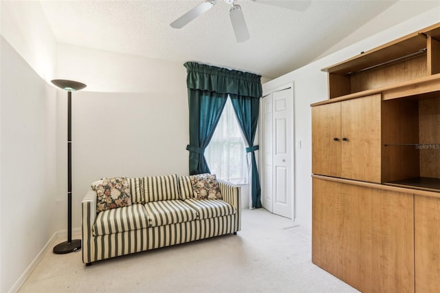 living area with vaulted ceiling, ceiling fan, and a textured ceiling