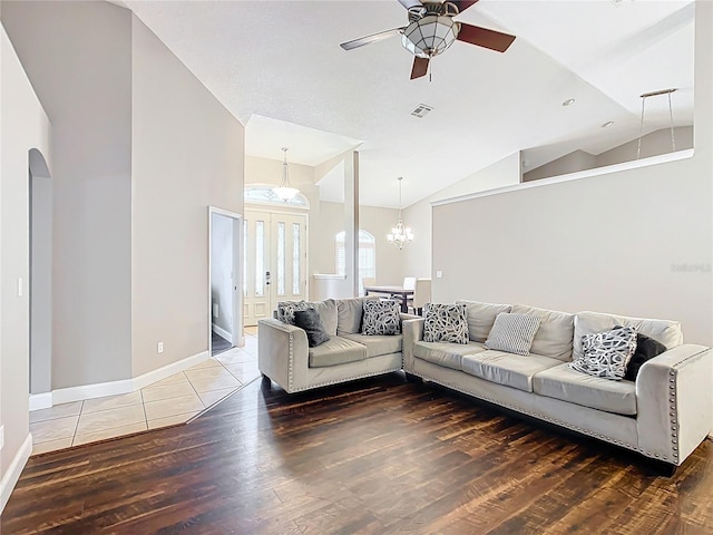 living room with ceiling fan with notable chandelier, vaulted ceiling, and hardwood / wood-style floors