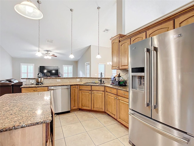 kitchen featuring ceiling fan, light stone countertops, hanging light fixtures, appliances with stainless steel finishes, and sink