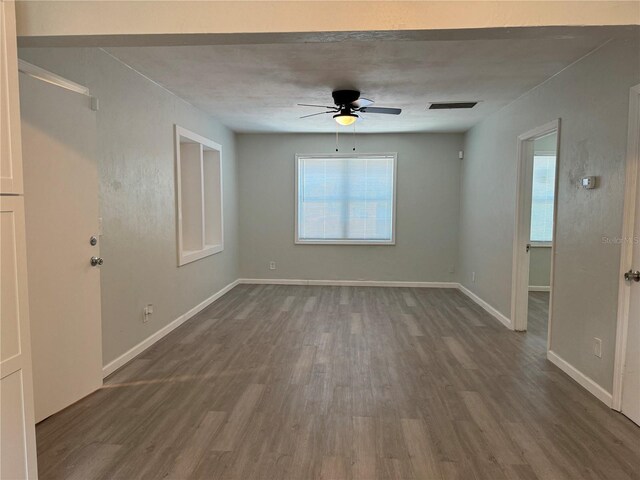 spare room featuring plenty of natural light, ceiling fan, and dark hardwood / wood-style floors