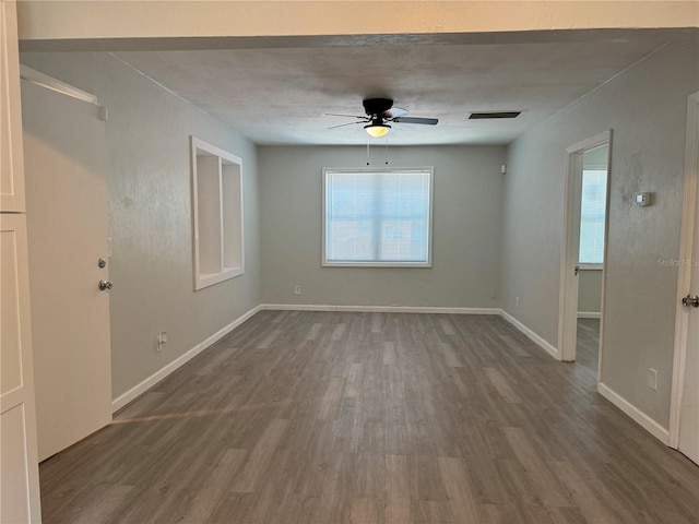 spare room with visible vents, a ceiling fan, baseboards, and wood finished floors